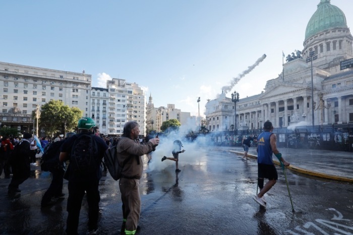 Ein Demonstrant wirft eine Tränengasgranate bei Zusammenstößen mit der Polizei während Protesten gegen Mileis Arbeitsmarktreform. Foto: EPA/Juan Ignacio Roncoroni