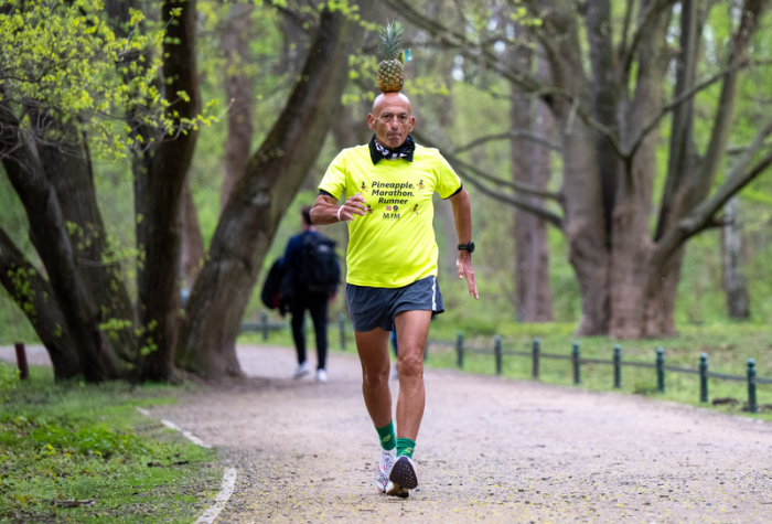 Moshe Lederfien, ein israelischer Marathon-Läufer, der bei seinen Läufen stets eine Ananas auf dem Kopf trägt, läuft durch den Tiergarten. Foto: Monika Skolimowska/dpa