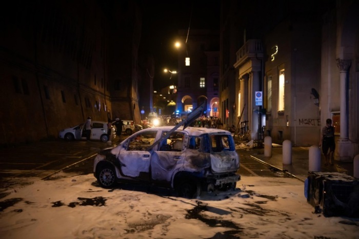 Ein beschädigtes Auto steht nach Zusammenstößen zwischen Demonstranten und der Polizei bei Protesten für den gestorbenen Marokkaner Abderrahim Fakir in Bologna. Foto: EPA/Max Cavallari