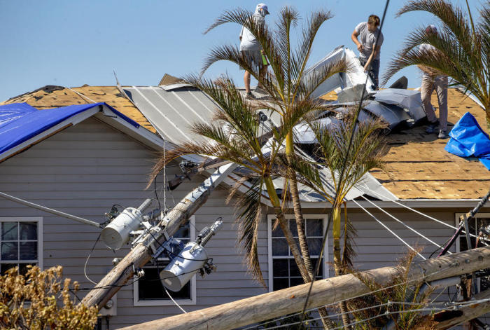 Leute reparieren ein Dach neben einem umgestürzten Strommast nach dem Durchzug des Hurrikans Ian in Matlacha Isles in Fort Myers Beach. Foto: epa/Cristobal Herrera-ulashkevich