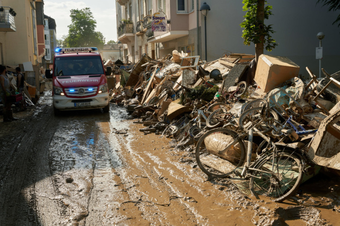 Ein Einsatzwagen der Feuerwehr fährt durch eine Straße, die mit Sperrmüll gesäumt ist. Foto: Thomas Frey/dpa