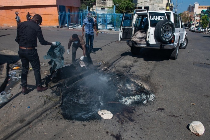 Angestellte der Stadtverwaltung sammeln die Überreste einer verbrannten Leiche ein, die auf einer Straße in Port-au-Prince gefunden wurde. Foto: epa/Johnson Sabin