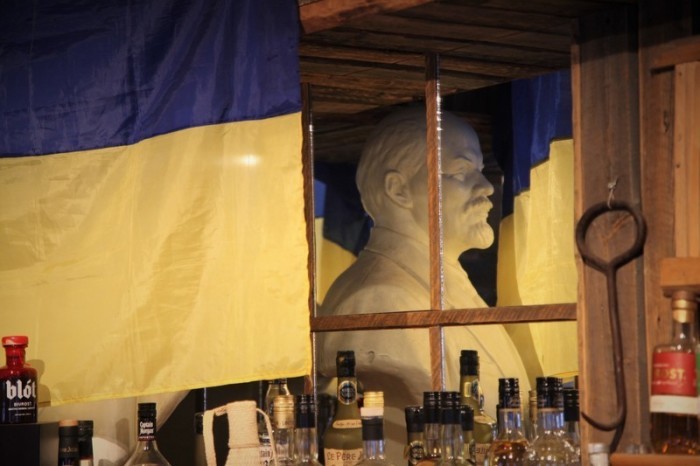 Eine Ukraine-Flagge hängt im Restaurant Kroa in Longyearbyen vor einer Büste des russischen Revolutionsführers Wladimir Iljitsch Lenin, die in einem Spiegel zu sehen ist. Foto: Steffen Trumpf/dpa