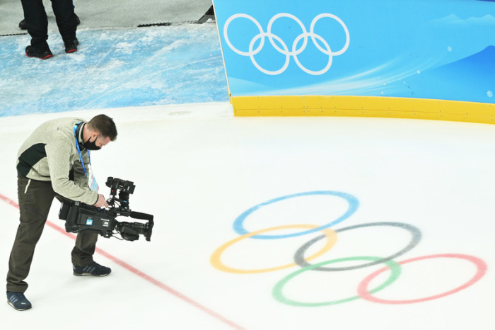 Ein Kameramann filmt die olympischen Ringe auf der Eisfläche im Nationalen Hallenstadion «The Fan». Hier werden olympische Eishockey-Spiele in Peking 2022 ausgetragen. Foto: Peter Kneffel/dpa