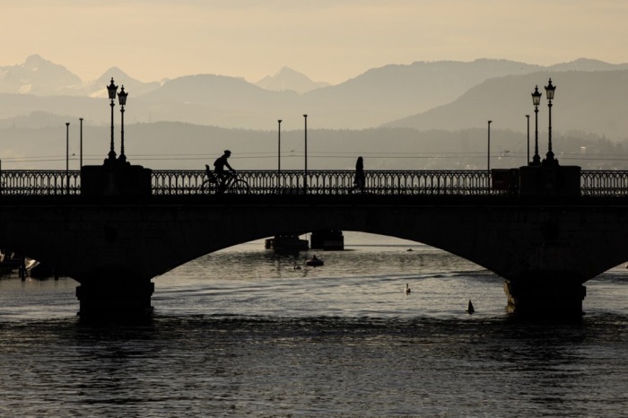 Ein Mann fährt mit dem Fahrrad über die Münsterbrücke in Zürich. Foto: epa/Michael Buholzer