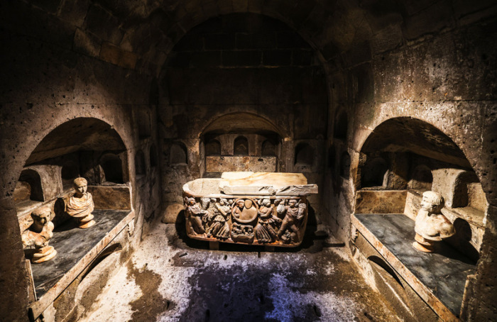 Ein Sarkophag und Büsten stehen in der Grabkammer des Römergrabes. Foto: Oliver Berg/dpa