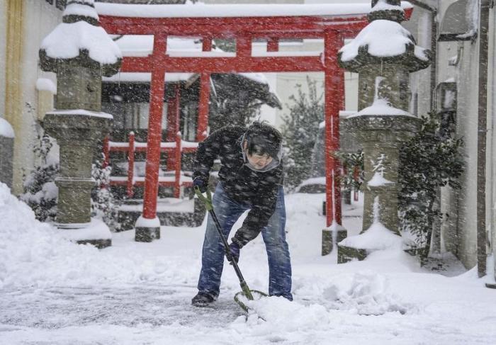 Ein Mann schaufelt Schnee vor einem Schrein. Schnee und Kälte haben weite Teile Japans heimgesucht und den Straßen-, Flug- und Zugverkehr behindert. Es wurden weitere Schneefälle und kalte Temperaturen vorher... Foto: Uncredited/Kyodo News/ap/dpa