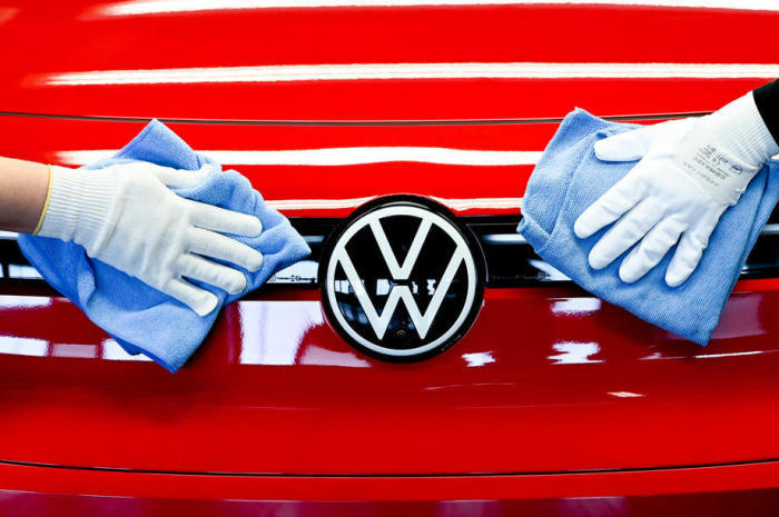 VW-Mitarbeiter säubern ein Volkswagen-Logo an einem Fließband für Elektroautos. Foto: epa/Filip Singer