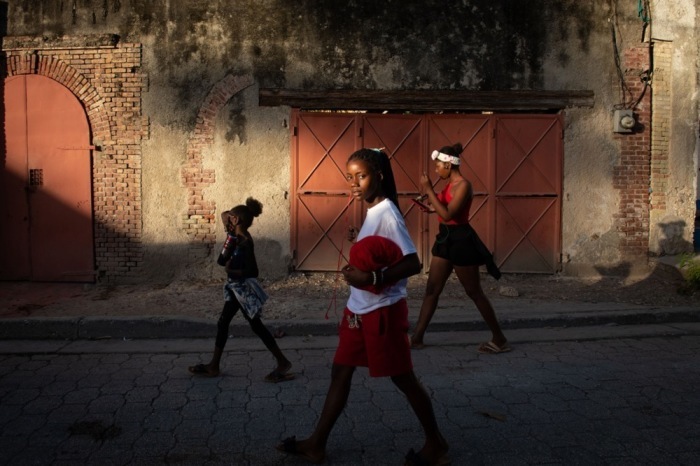 Mädchen gehen bei Sonnenuntergang durch eine Straße in Jacmel. Die Küstenstadt zeigt den Alltag fernab politischer Krisen. Foto: epa/Johnson Sabin