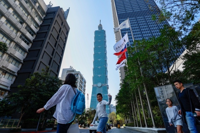 Menschen gehen in Taipeh an einer Taiwan-Flagge vorbei, während das Land im Vorfeld der Präsidentschaftswahl im Zeichen politischer Spannung steht. Foto: EPA/Daniel Ceng