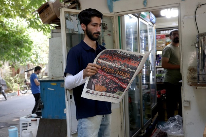 Ein Mann liest in Teheran eine Zeitung mit Bildern von Ali Khameneis Beisetzung und dessen Sohn Mojtaba Khamenei. Foto: Abedin Taherkenareh/epa