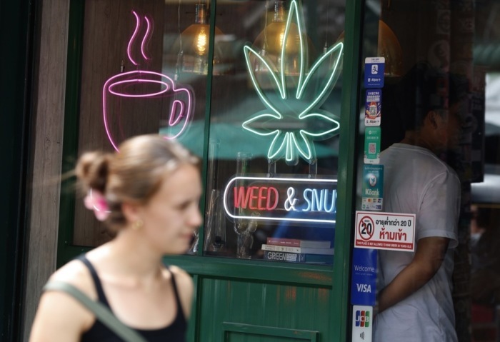 Eine ausländische Touristin geht an einem Cannabis-Shop in der beliebten Touristenstraße Khaosan Road in Bangkok vorbei. Foto: epa-efe/Narong Sangnak