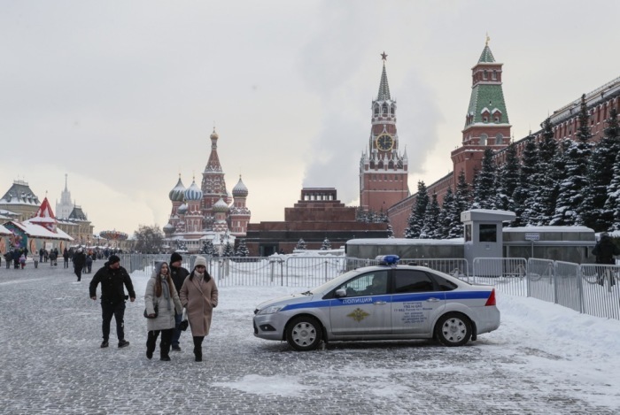 Leute gehen neben einem Polizeiauto, das vor dem Moskauer Kreml und dem Lenin-Mausoleum auf dem Roten Platz in Moskau Wache steht. Foto: epa/Yuri Kochetkov