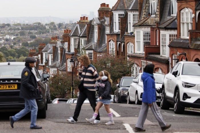 Leute gehen an einer Häuserreihe im Norden Londons vorbei. Archivfoto: epa/TOLGA AKMEN