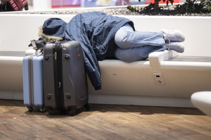 Ein gestrandeter Fluggast schläft auf einer Bank am Flughafen Frankfurt. Foto: Boris Roessler/dpa