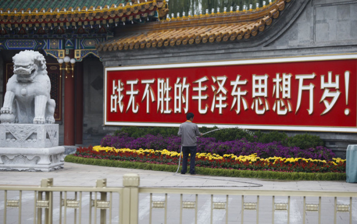 Ein Arbeiter in Peking wässert Pflanzen in der Nähe eines Schildes: 