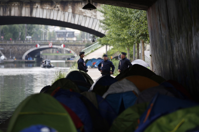 Polizisten bewachen ein Zeltlager, während dieses geräumt wird. Foto: Thibault Camus/Ap/dpa