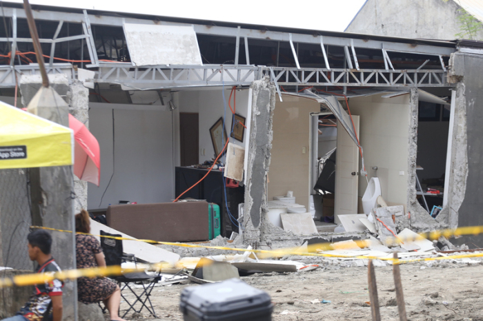 Anwohner sitzen neben einem beschädigten Haus nach einem starken Erdbeben im Süden der Philippinen. Foto: Manman Dejeto/Ap/dpa