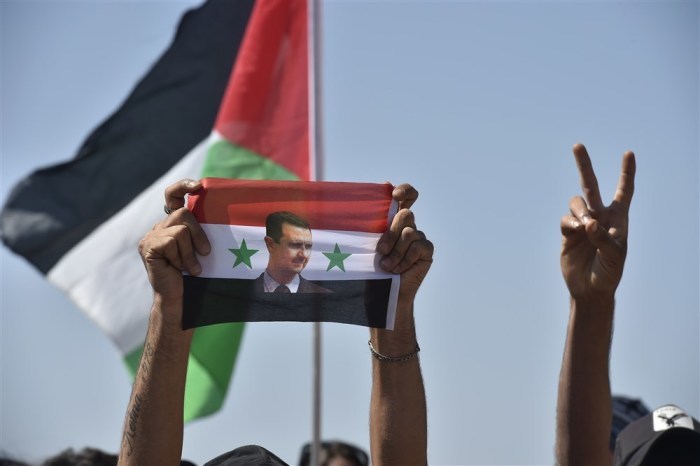 Ein Mensch hält eine syrische Flagge mit einem Foto von Präsident Bashar Assad in die Höhe, während arabische Jugendliche an einem Sommerlager teilnehmen. Archivfoto: epa/WAEL HAMZEH