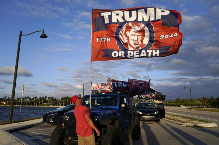 Ein Anhänger des ehemaligen PräsidentenTrump hisst eine Flagge vor Trumps Anwesen Mar-a-Lago. Foto: Lynne Sladky/Ap/dpa