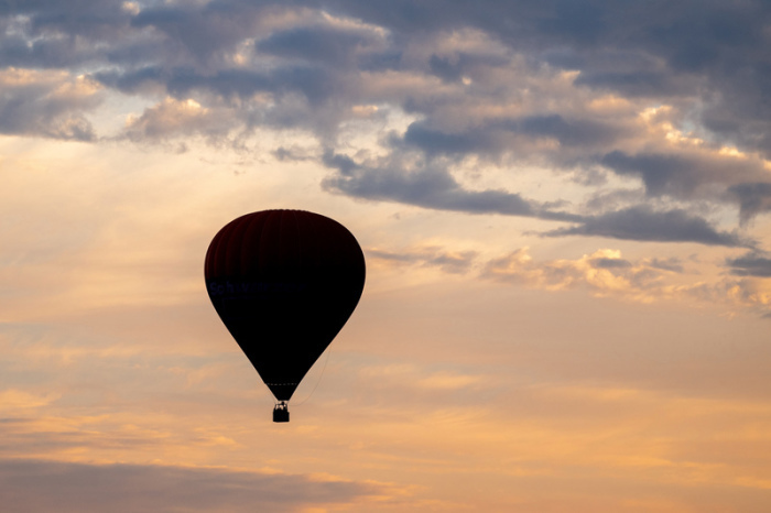 Ein Heißluftballon fährt am frühen Morgen vor dem leicht bewölkten Himmel über den Feldern und Wiesen in der Wesermarsch. Foto: Hauke-Christian Dittrich/dpa