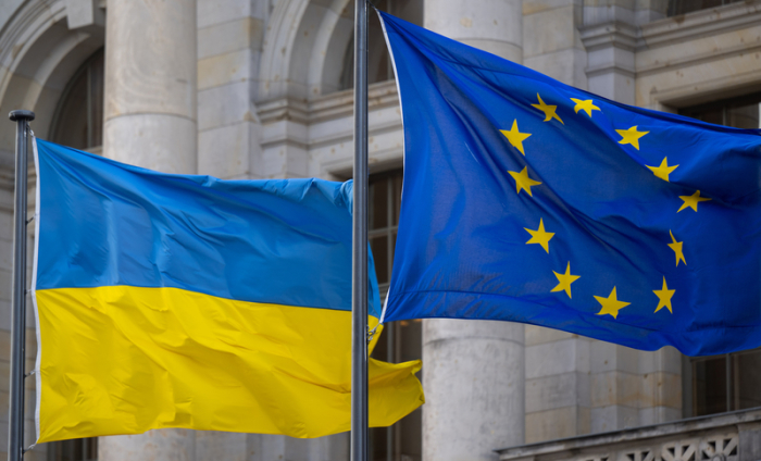 Die Nationalflagge der Ukraine und die Flagge der EU wehen im Wind. Foto: Monika Skolimowska/dpa
