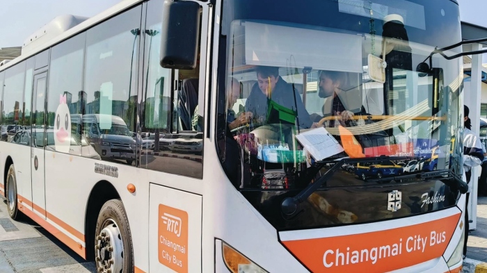 Ein einsamer blauer Stadtbus fährt durch eine belebte Straße in Chiang Mai, vorbei an wartenden Fahrgästen am Straßenrand. Foto: Prachachat