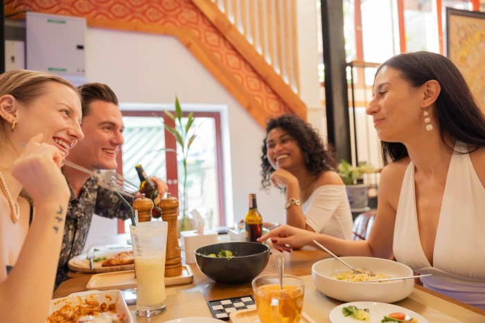 Freunde genießen gemeinsam ein Essen in einem Restaurant, während Getränke und Speisen am Tisch stehen. Foto: Unsplash/Adhd Creative Co.