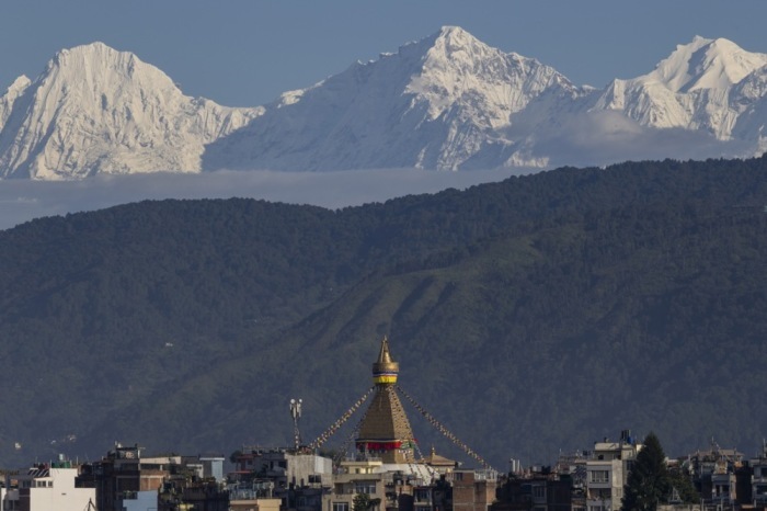 Das Ganesh-Himal-Gebirge erhebt sich bei klarem Wetter hinter einer Buddha-Stupa in Kathmandu. Die Szene zeigt den Alltag in Nepals Hauptstadt. Foto: epa/Narendra Shrestha
