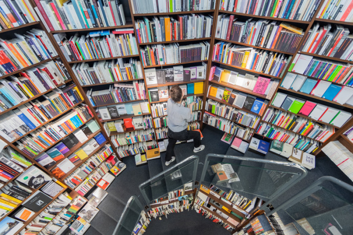 Eine Mitarbeiterin sortiert in der Buchhandlung Walther König Bücher in Regale ein. Foto: Rolf Vennenbernd/dpa