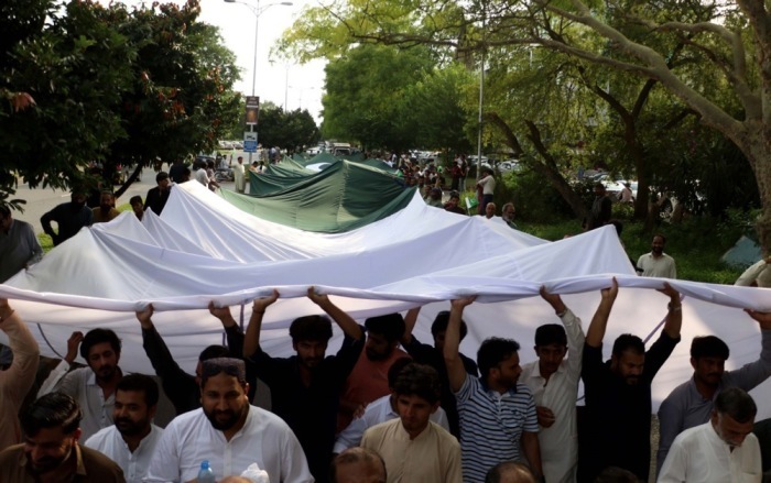 Menschen tragen eine große pakistanische Flagge, während sie vor den Feierlichkeiten zum Unabhängigkeitstag in Islamabad auf einer Straße marschieren. Foto: epa/Sohail Shahzad