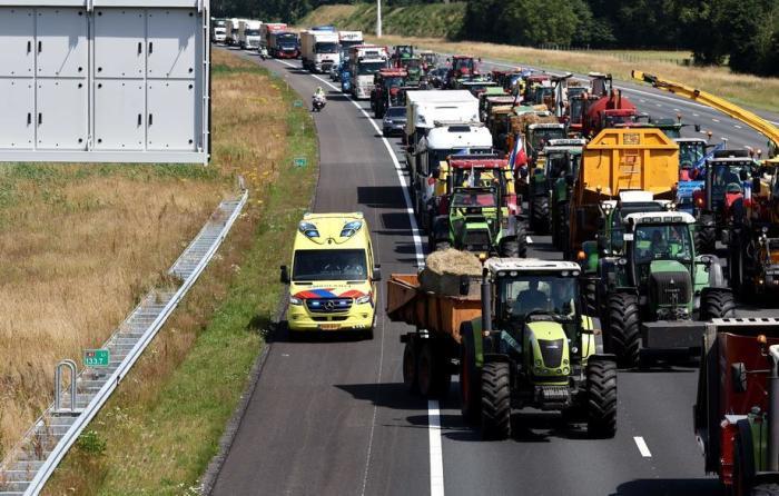 Ein Krankenwagen fährt auf der Autobahn A1 an Traktoren vorbei, während Landwirte in der Nähe von Oldenzaal gegen die Stickstoffpläne der Regierung protestieren. Foto: epa/Vincent Jannink