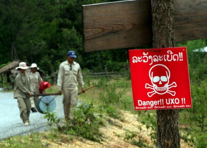 Das Team von UXO Laos (Unexploded Ordinance Laos) trägt den Auslösedraht zur Sprengung einer Mörsergranate und anderer Blindgänger auf einem Feld im Dorf Sam Syae in der Nähe von Phonsavan. Foto: epa/Barbara Walton