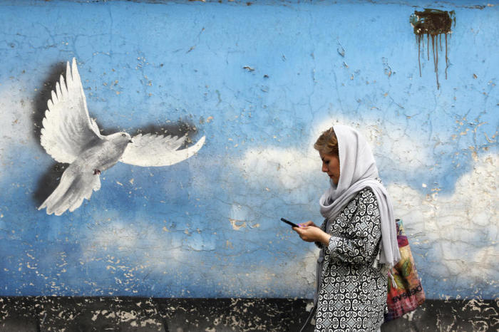 Eine Frau aus dem Iran geht an einem Wandgemälde mit einem Friedensvogel in einer Straße in der Innenstadt vorbei. Foto: epa/Abedin Taherkenareh