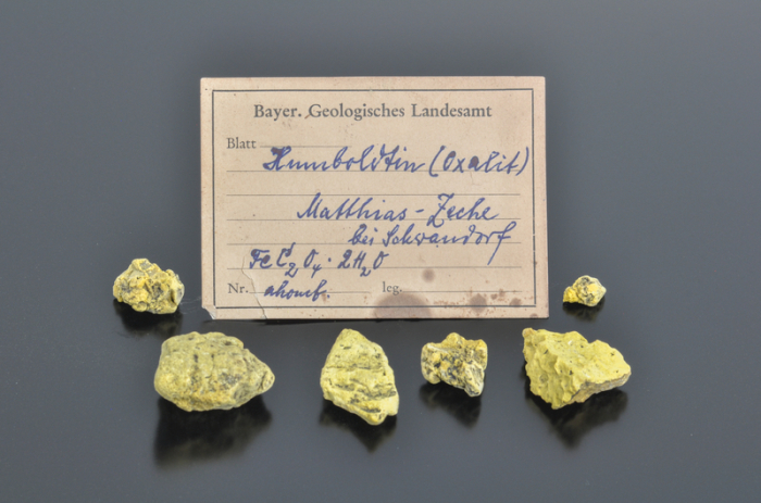 Neben einem handgeschriebenen Etikett liegen Stücke des Minerals Humboldtin. Foto: Kemner/Lfu/dpa