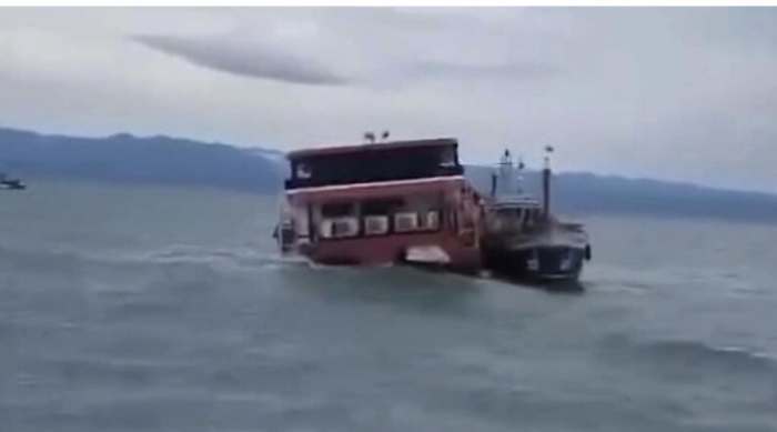 Das beschädigte Passagierboot neigt sich stark zur Seite, während Einsatzkräfte es bei rauer See sichern. Foto: Khaosod