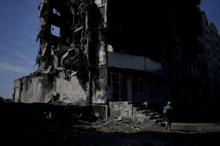 Eine Frau geht an einem durch russischen Beschuss zerstörten Gebäude in Borodjanka am Stadtrand von Kiew vorbei. Foto: Natacha Pisarenko