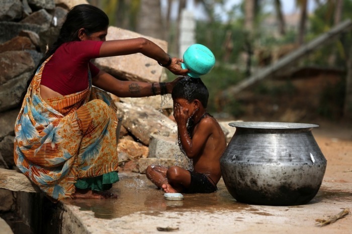 Eine Inderin badet ihr Kind zur Abkühlung bei großer Hitze. Foto: epa/Jagadeesh Nv
