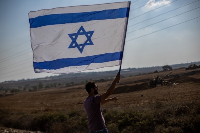 In der Nähe einer israelischen Artillerieeinheit an der Grenze zum Gazastreifen winkt ein Mann mit einer israelischen Flagge. Foto: epa/Martin Divisek