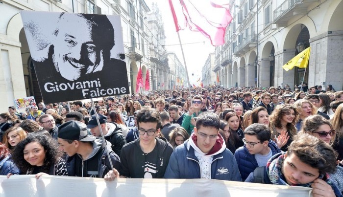 Menschen halten Plakate mit dem Bild des Mafiaopfers Giovanni Falcone hoch. Foto: epa/Alessandro Di Marco