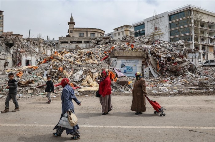 Am Vorabend des Ramadan gehen Frauen mit Einkaufstüten vor eingestürzten Gebäuden spazieren. Foto: epa/Erdem Sahin