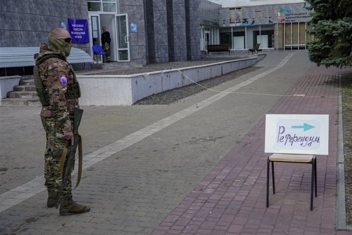 Ein bewaffnetes russisches Mitglied der Armee steht neben einem Schild mit der Aufschrift 