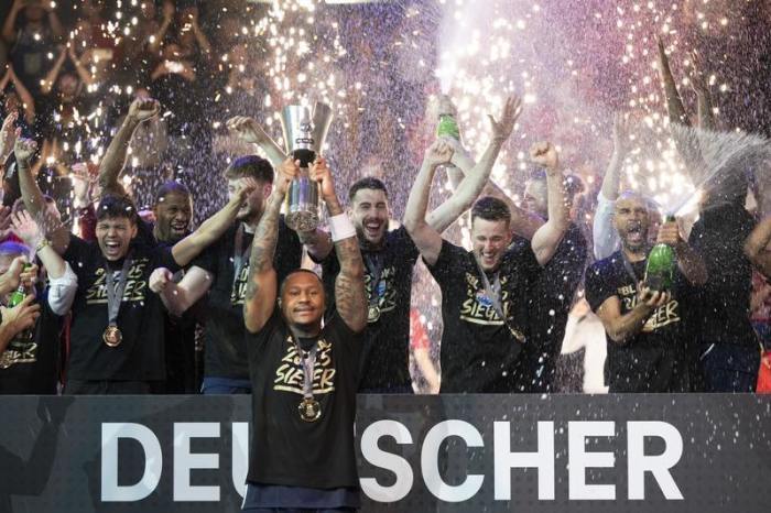 BBL-Pokal, Syntainics MBC Weißenfels - Bamberg Baskets, Final Four, Finale, Stadthalle Weißenfels. Weißenfels' Charles Callison (vorne) hebt nach dem Sieg den Pokal hoch während seine Teamkollegen feiern. Foto: Sebastian Kahnert/dpa
