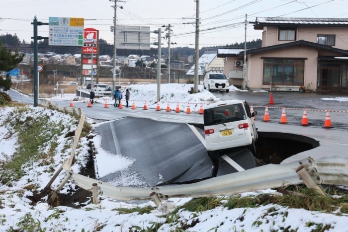 Ein Auto steckt auf einer eingestürzten Straße fest, nachdem ein starkes Beben den Nordosten Japans erschüttert und Schäden verursacht hat. Foto: EPA/Jiji Press