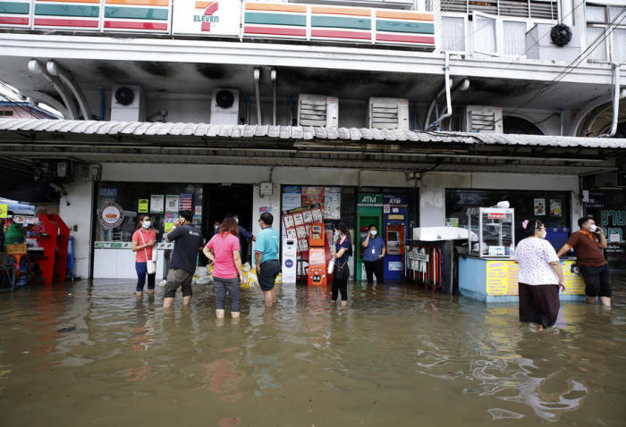 Durch das Hochwasser hindurch watende Thailänder in der Nähe des Flusses Chao Phraya in Bangkok. Foto: epa/Narong Sangnak
