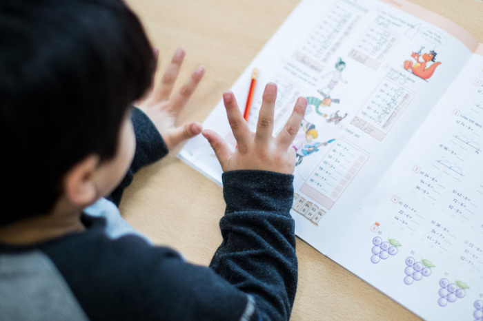 Ein Junge rechnet im Klassenraum einer Grundschule in Essen (Nordrhein-Westfalen) während einer Mathe-Übung mit den Fingern. Foto: Marcel Kusch/dpa