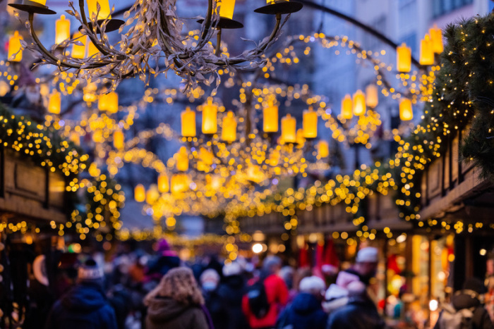 Besucher gehen über den Weihnachtsmarkt am Alter Markt. Viele Städte prüfen, wie sie bei der Weihnachtsbeleuchtung Energie sparen können. Foto: Rolf Vennenbernd/dpa