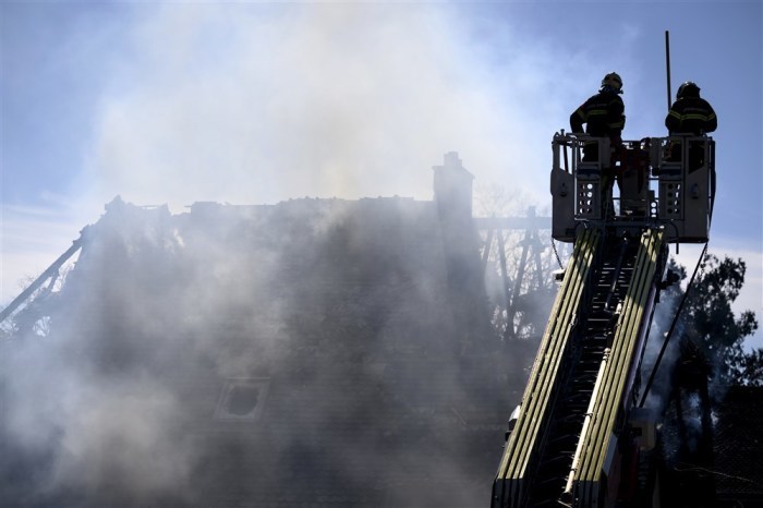Feuerwehrleute auf einer Leiter nähern sich einer Villa, aus der nach einem Brand in Yverdon-les-Bains Rauch aufsteigt. Foto: epa/Jean-christophe Bott