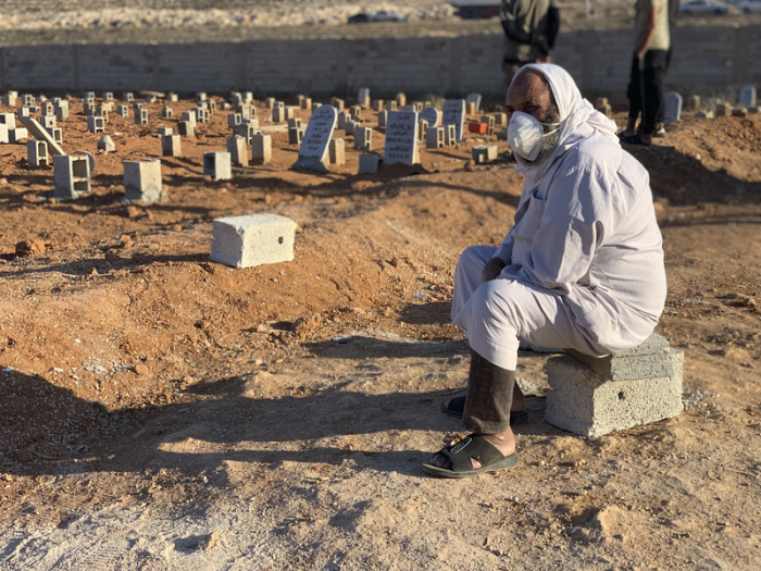 Ein Mann sitzt neben den Gräbern der Opfer der Sturzflut. Foto: Yousef Murad/Ap/dpa