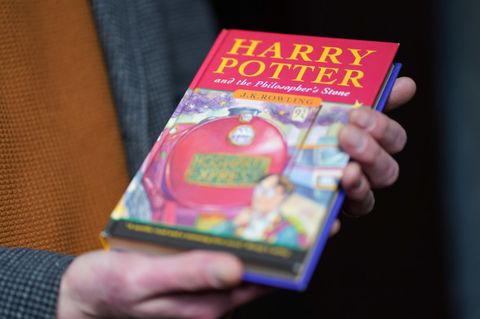 Auktionator Jim Spencer hält eine makellose Erstausgabe von J.K. Rowlings des Harry-Potter-Bands «Der Stein der Weisen» («The Philosopher's Stone») in der Hand. Foto: Jacob King/Pa Wire/dpa
